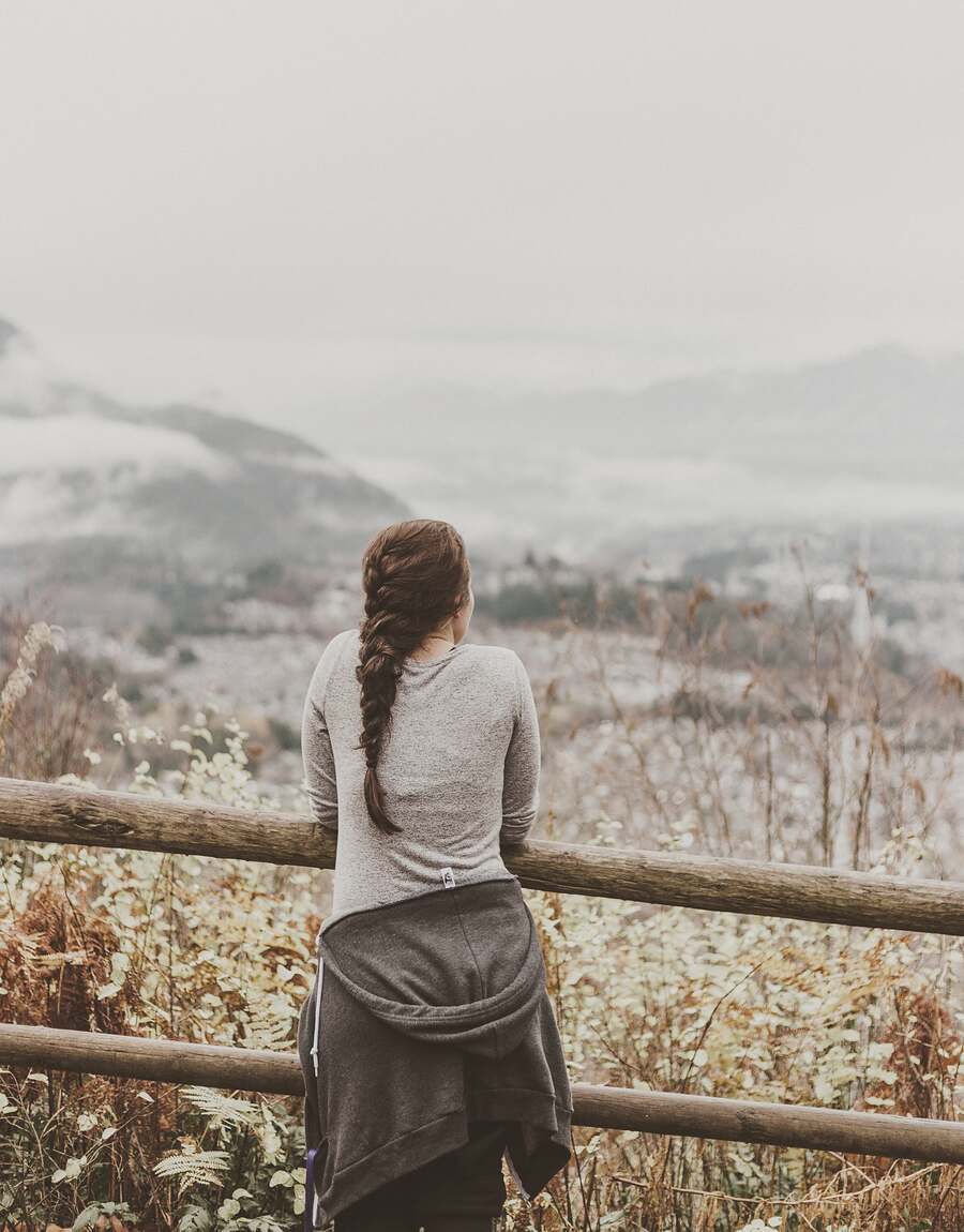 A woman at a railing looking out over a misty valley